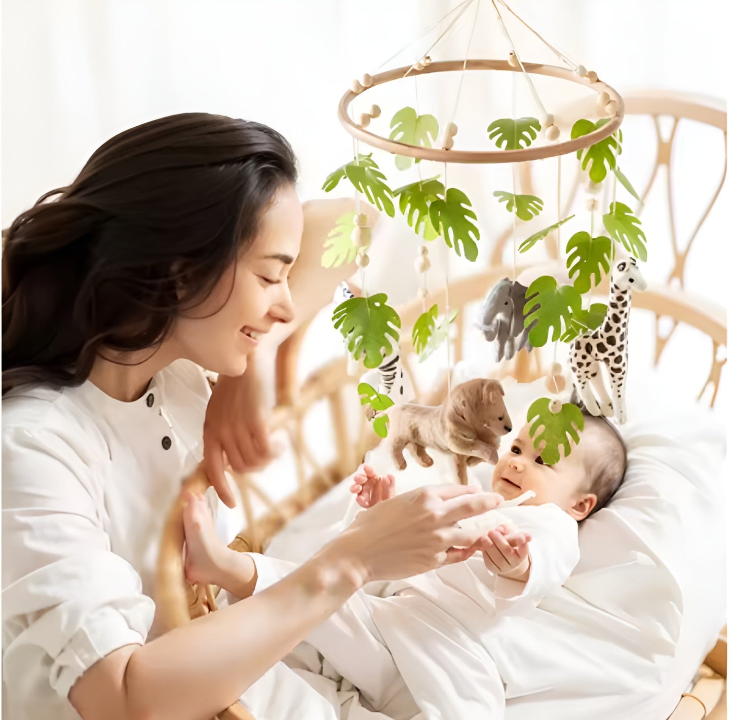 Babymobil med djur och gröna blad ovanför bebis i säng