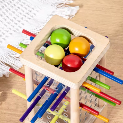 Närbild ovanifrån på färgade kulor och pinnar i montessorileksak i trä