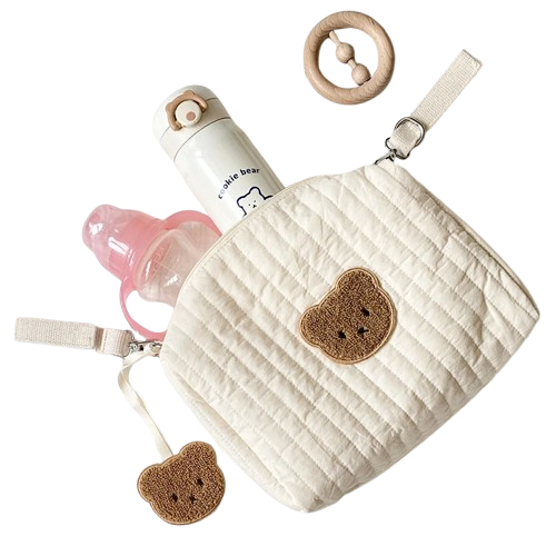 Quiltad organizer skötväska med björnmotiv, nappflaska och skallra mot transparent bakgrund