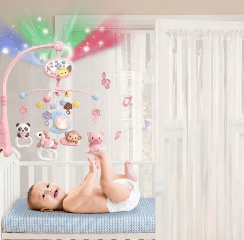 Rosa babymobil med projektor, musik och djurfigurer ovanför bebis i spjälsäng