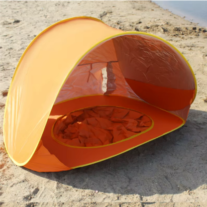 Orange pop-up UV-tält uppställt på sandstrand i sned vinkel
